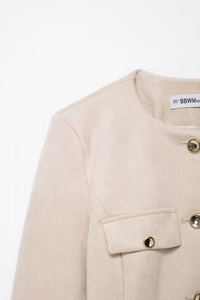 Dettaglio della giacca scamosciata beige con trama fine e bottone in metallo dorato