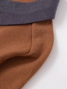Détails des coutures contrastées d'un polo en tricot bicolore gris foncé et marron caramel