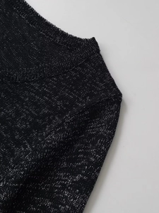 Détail du haut en tricot noir avec fils métalliques argentés et couture d'épaule