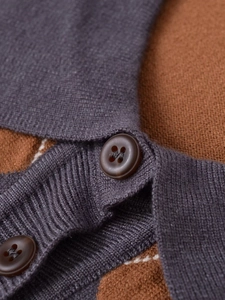 Détail de la texture de maille fine et des boutons marron sur le cardigan à motif losanges