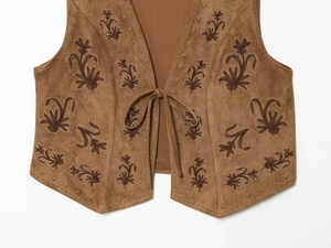 Detailed view of floral embroidery and lace-up closure on brown suede vest