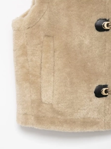 Dettaglio del gilet in pile cammello con fibbia in pelle nera e chiusura in metallo dorato