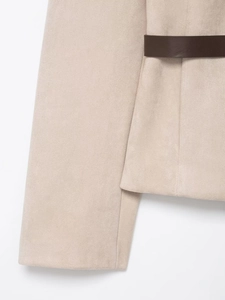 Dettaglio del tessuto scamosciato sintetico e cintura in pelle marrone sul blazer