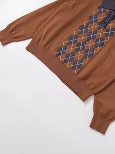 Détail d'un polo en maille marron à losanges avec boutons sombres et finitions côtelées