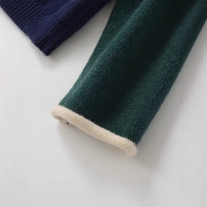 Close-up of contrast patchwork knit cardigan with forest green and navy wool texture