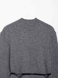 Gros plan sur la maille grise du cardigan avec une fine ceinture noire décorative