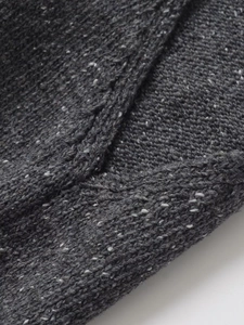 Close-up of thick grey knit texture with speckled yarn details on high-neck top