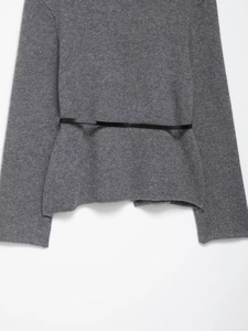 Détail de la texture d'un gilet en maille gris foncé avec fine ceinture en cuir noir