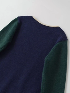 Close-up of contrast knit sweater neckline with navy body and green sleeves