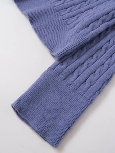 Detailed close-up of purple cable knit sweater showing textured weave and ribbed cuffs