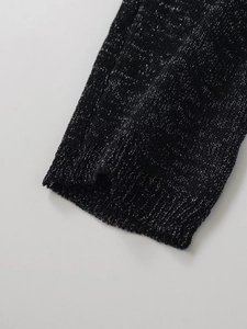Gros plan sur la maille noire métallisée montrant la texture et les fils argentés brillants