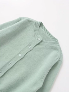 Close-up of mint green knit cardigan collar with ribbed edges and white buttons