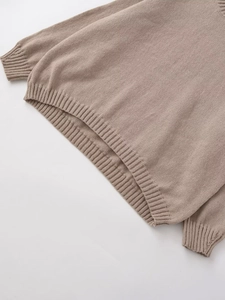 Close-up of khaki knit sweater showing ribbed cuffs and textured stitching detail