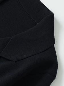 Detail view of premium black knit fabric with refined stitching on the polo collar and shoulder