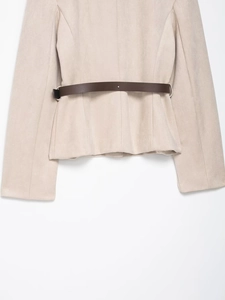Dettaglio del blazer in finta pelle scamosciata beige con sottile cintura in pelle marrone