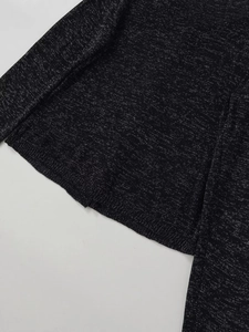 Détail d'un haut en maille noire avec fil métallique argenté et texture scintillante