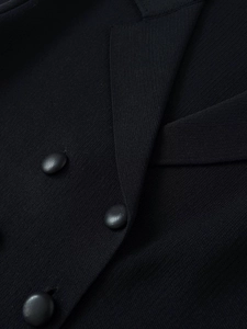 Macro shot of high-density black knit fabric texture and textured round buttons