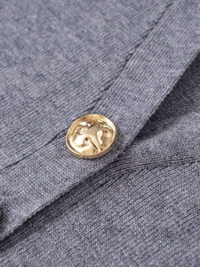 Detail of grey knitted cardigan showing soft fabric texture and embossed gold metal button