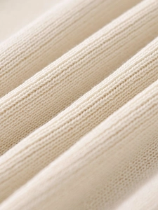 Macro shot of warm beige ribbed knit fabric texture showing high-quality soft fibers