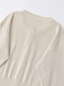 Detailed view of ivory knit sweater collar and shoulder seams with ribbed neckline