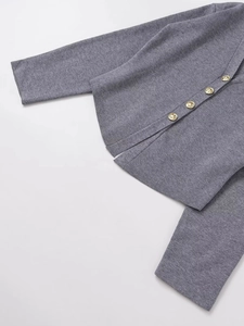 Detailed view of grey knit cardigan featuring golden lion-embossed metal buttons