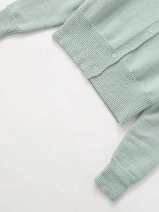 Detail of mint green knit cardigan featuring ribbed hem and matching round buttons