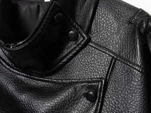 Gros plan sur la texture du simili cuir noir avec coutures fines et bouton-pression mat