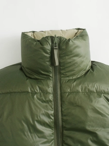Detail of olive green quilted vest with high collar and tonal resin zipper puller