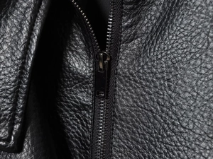 Détail macro du cuir noir texturé litchi avec une fermeture éclair métallique élégante
