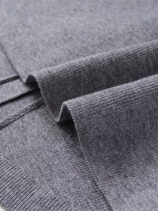 Close-up detail of soft grey knit fabric texture with ribbed edge finishing