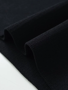 Macro shot of high-quality black fine-knit fabric with detailed ribbed texture and soft drape