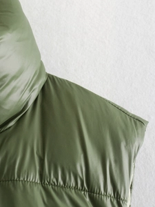 Detail of olive green quilted puffer vest with glossy finish and high-quality stitching