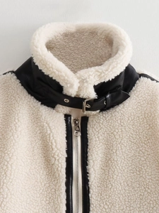 Detail of faux shearling jacket featuring black faux leather trim and metal belt buckle