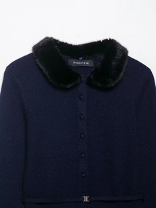 Detail of navy knit cardigan featuring black faux fur collar and golden metallic hardware