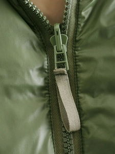 Detailed macro view of olive green quilted vest with a durable matching zipper