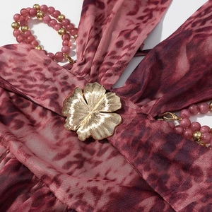 Détail de la robe en tulle léopard avec boucle fleurie dorée et bandoulière en perles