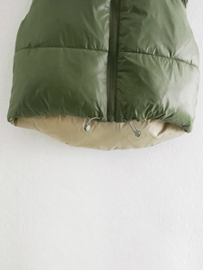 Detail of olive green quilted vest hem with adjustable drawstring and resin zipper