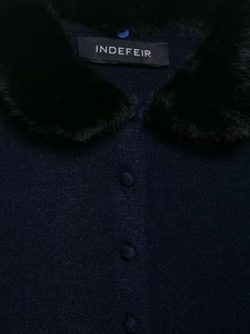 Close-up of navy knit cardigan with plush black faux fur collar and fabric buttons