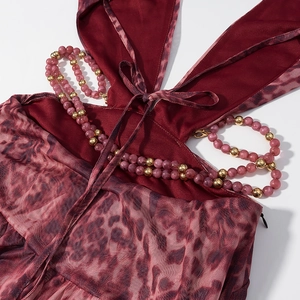 Détail de robe en résille léopard rouge avec chaîne perlée et nouage licou au cou