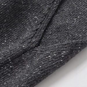 Detailed view of dark grey marled knit fabric with dense wool blend texture