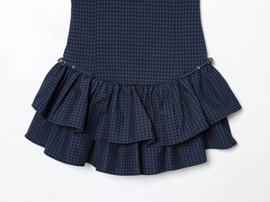 Close-up of tiered plaid skirt hem with ruffled layers and decorative metal ring buckles