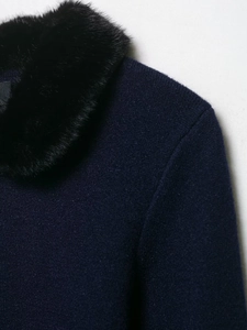 Close-up of navy knit cardigan featuring a plush black faux fur collar and fine stitching