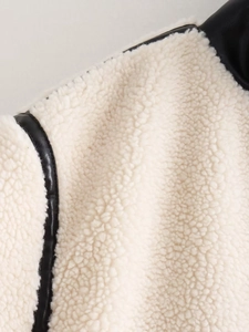 Detailed view of cream faux fur texture with contrasting black leather trim stitching