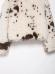 Detail of faux fur coat hem featuring plush white texture with dark brown animal spots