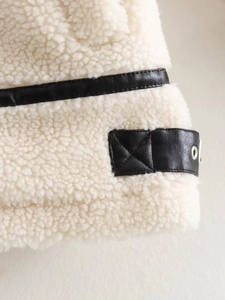 Detailed macro view of white faux shearling jacket with black faux leather trim and eyelets