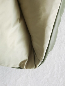 Close-up of olive green quilted vest showing smooth beige lining and premium stitching