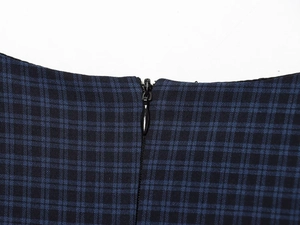 Close-up of high-quality invisible zipper on a navy plaid textured fabric dress