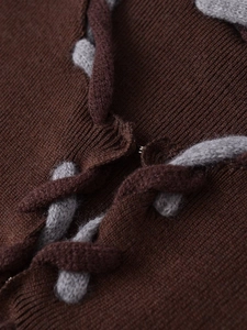 Détail de veste en maille avec liens entrelacés gris et attache en crochet métallique