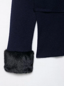 Close-up of navy knit cardigan featuring black faux fur cuffs and a side slit hem detail