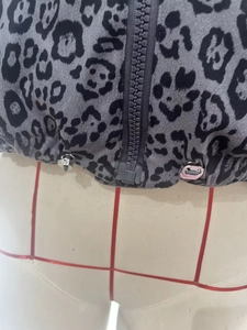 Close-up of leopard print vest featuring a gray zipper and adjustable drawstring hem detail